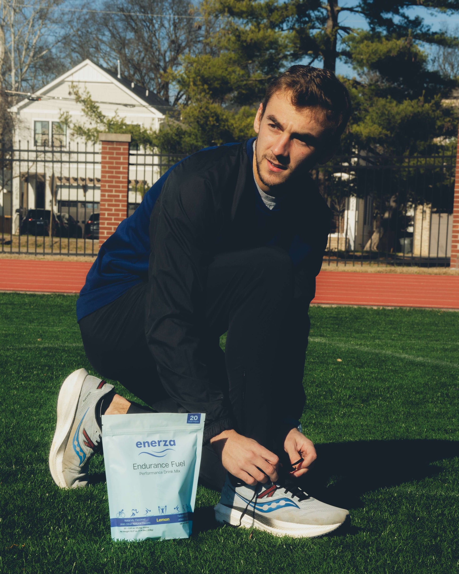 Enerza Endurance Fuel package in the foreground with a male runner tying shoes in the background, symbolizing energy and preparation for high-performance athletic training.