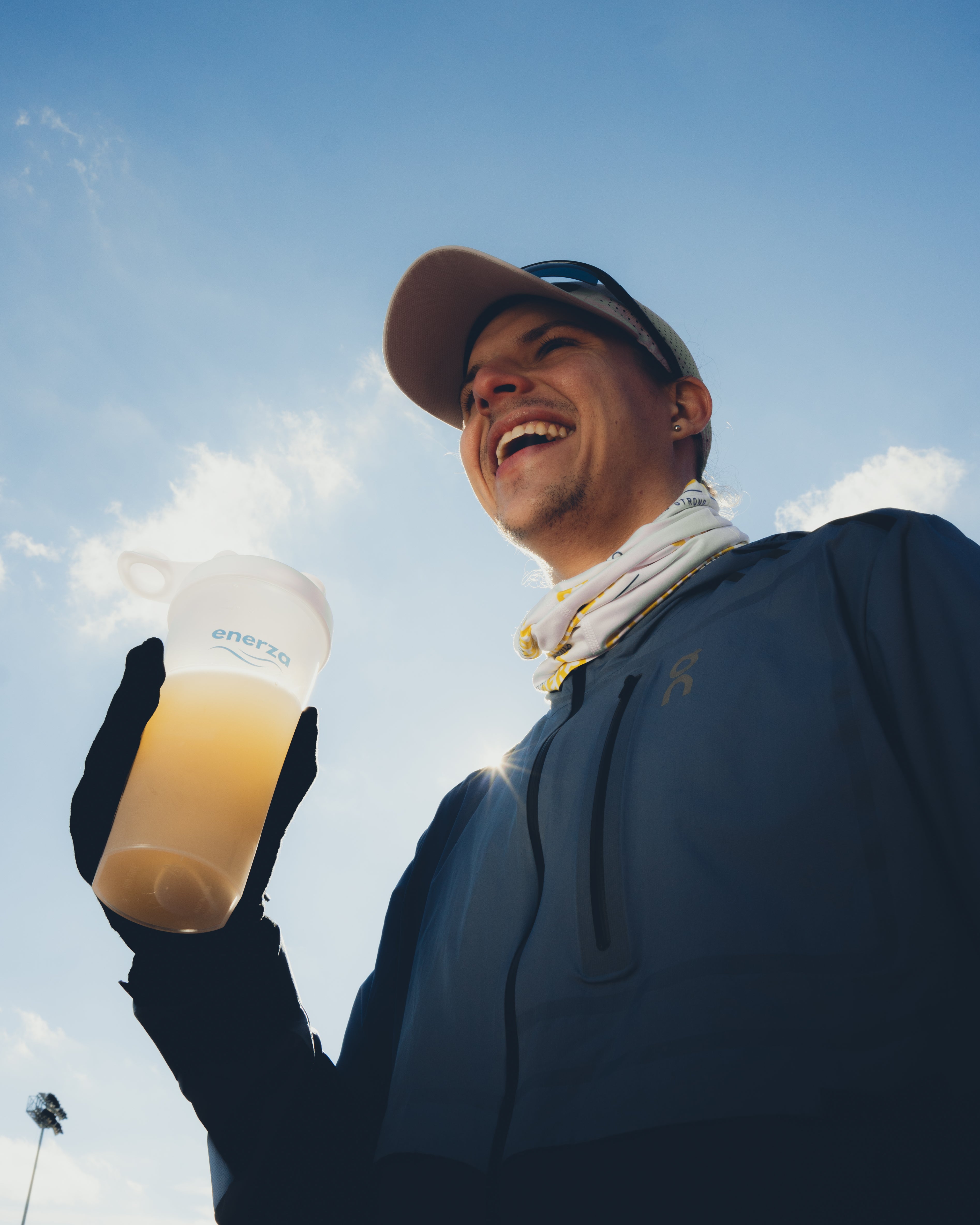 Male runner holding a shaker bottle of Enerza endurance fuel, emphasizing performance for endurance athletes.